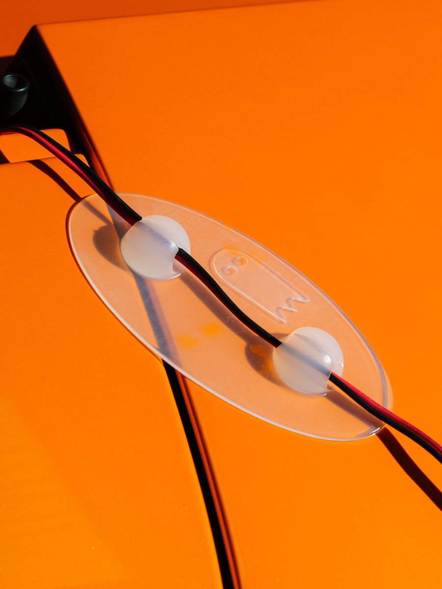Clear Ghost Guard holding a red cable on an orange car