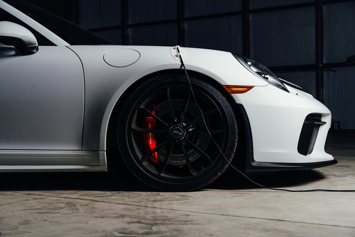 White sports car charging with Ghost Guard in a dark garage