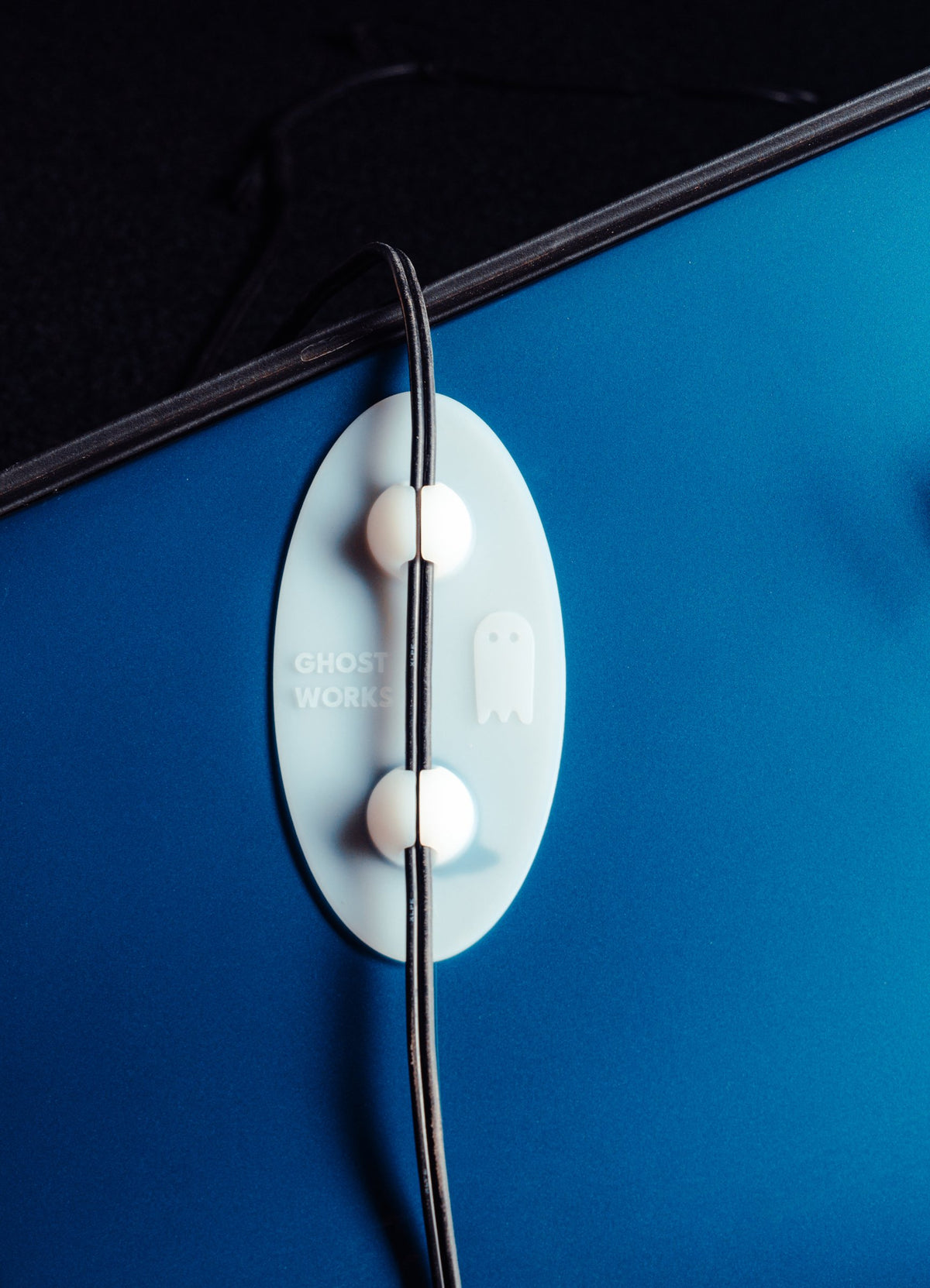 Ghost Guard holding a charging cable away from a blue car's paint