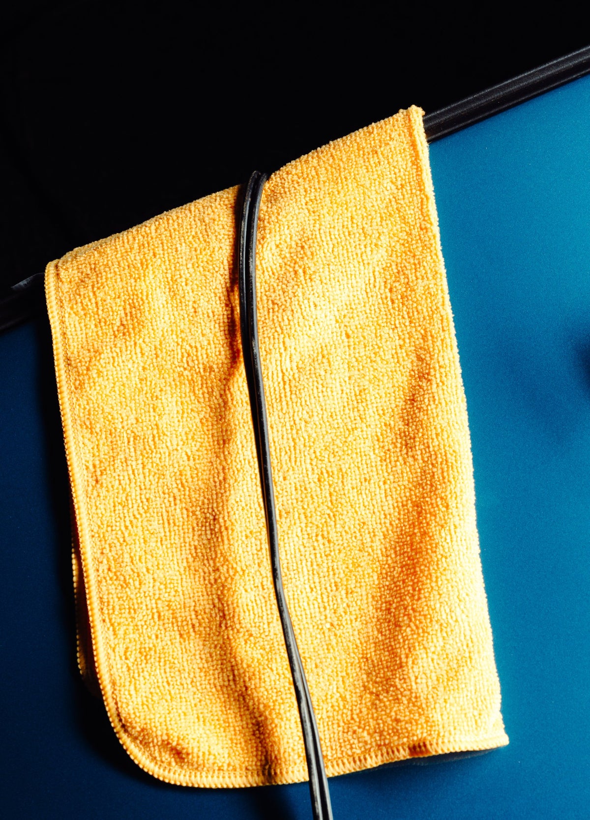 Charging cable resting on a towel against a blue car